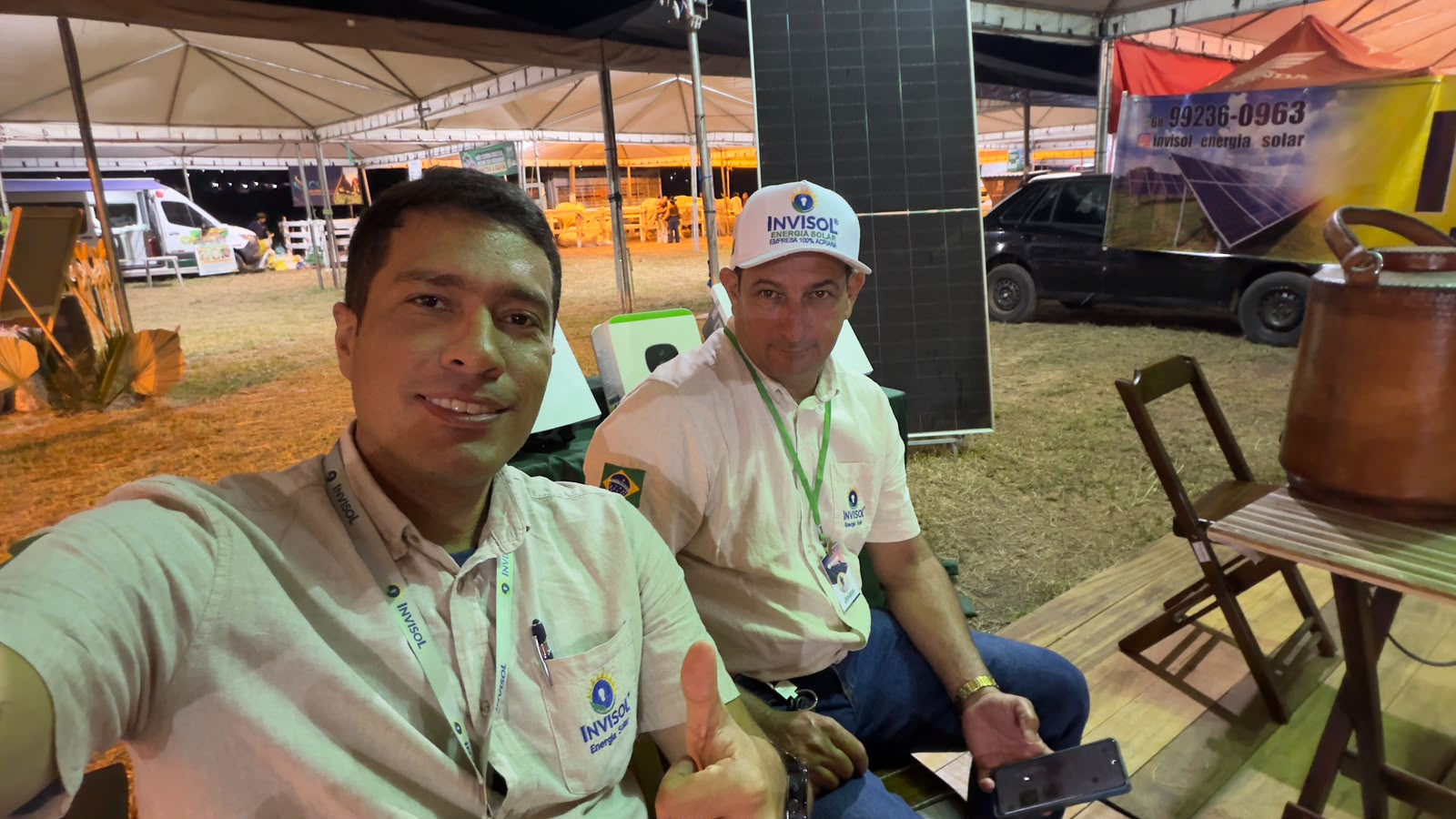 Equipe InviSol em estande de evento com painel solar ao fundo
